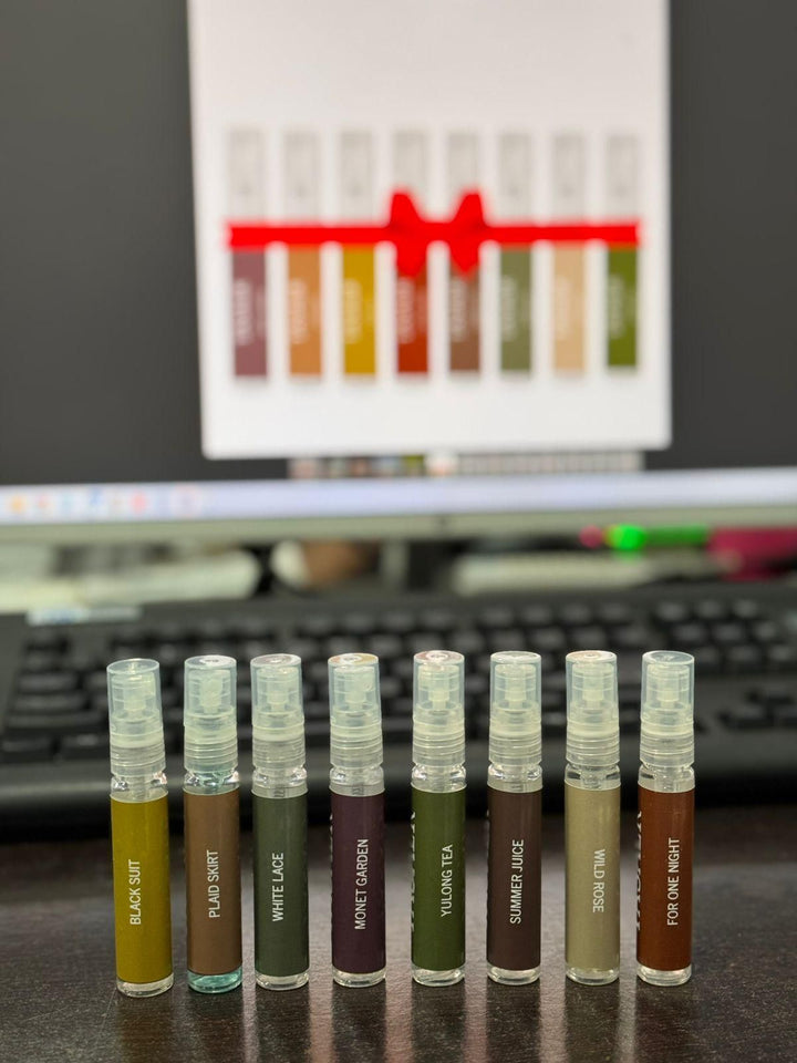 Set of 8 small perfume spray bottles from 8 Perfumes Gift Box displayed in a row on a desk