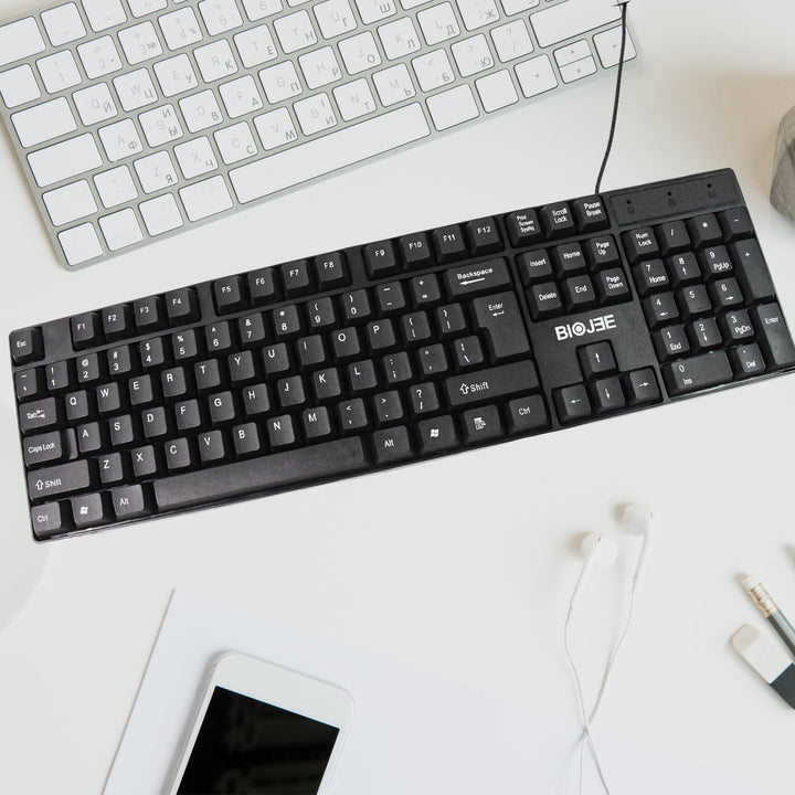 Superior eMart 104 key office keyboard in black on a workspace with a smartphone and headphones