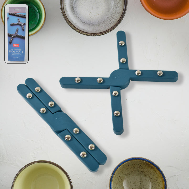 Foldable pan stand for hot pots in blue metal with silver rivets on a kitchen countertop with bowls