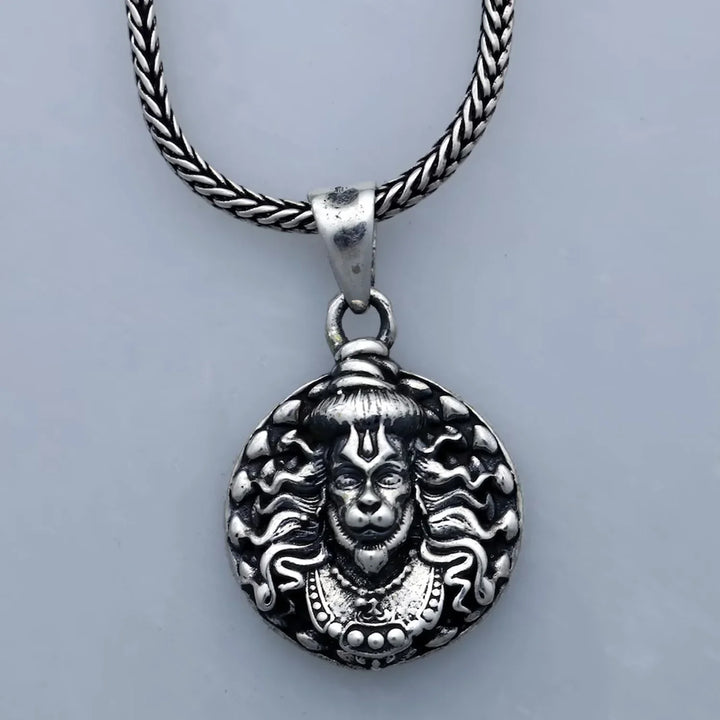 Hanuman facelocket necklace with intricate silver design and braided metal chain