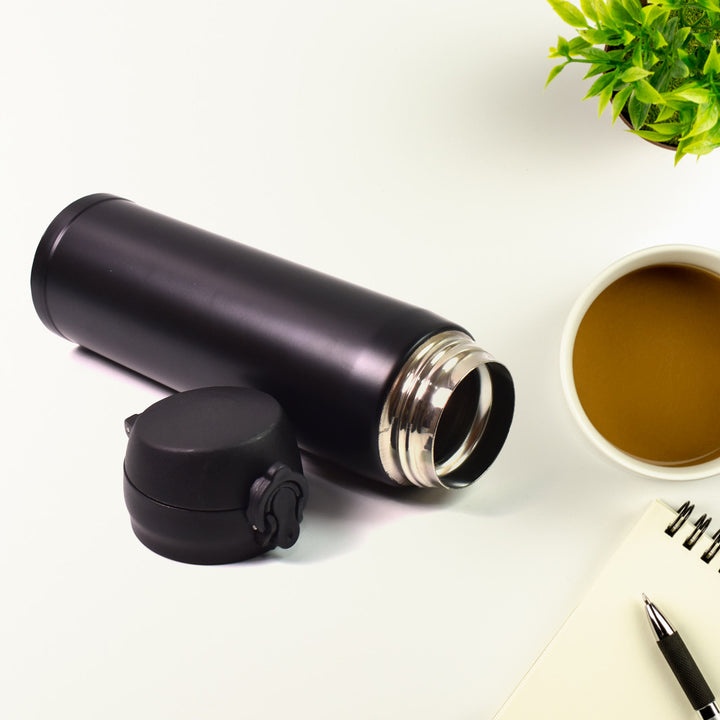 500 ml insulated kids water bottle in black with a spill-proof lid next to a notepad and coffee cup