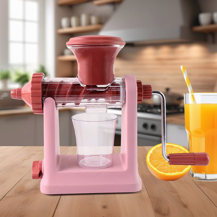 Superior eMart pink manual juicer for home use with glass cup and fresh orange juice on wooden kitchen counter