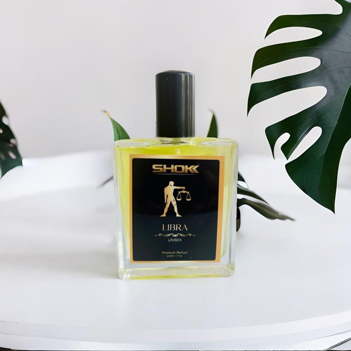 SHOK Libra Zodiac Unisex Perfum 50ml bottle with black cap on white surface with green leaves background