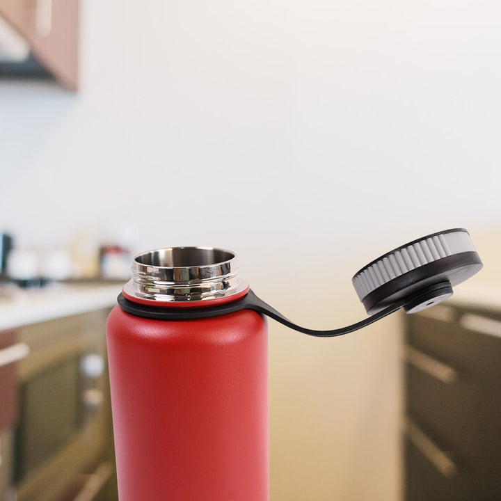Red stainless steel vacuum bottle 1000ml with an open black lid on a kitchen countertop