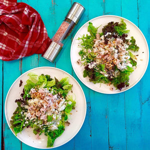 2-in-1 salt and pepper grinder beside two fresh salads on a blue table, enhancing flavor with ease