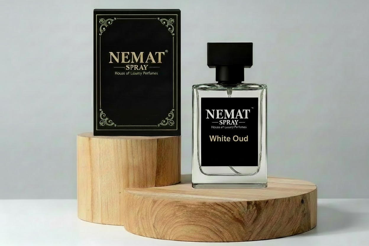 Nemat White Oud spray perfume bottle and black box on wooden pedestals. Clear glass bottle with black square cap.