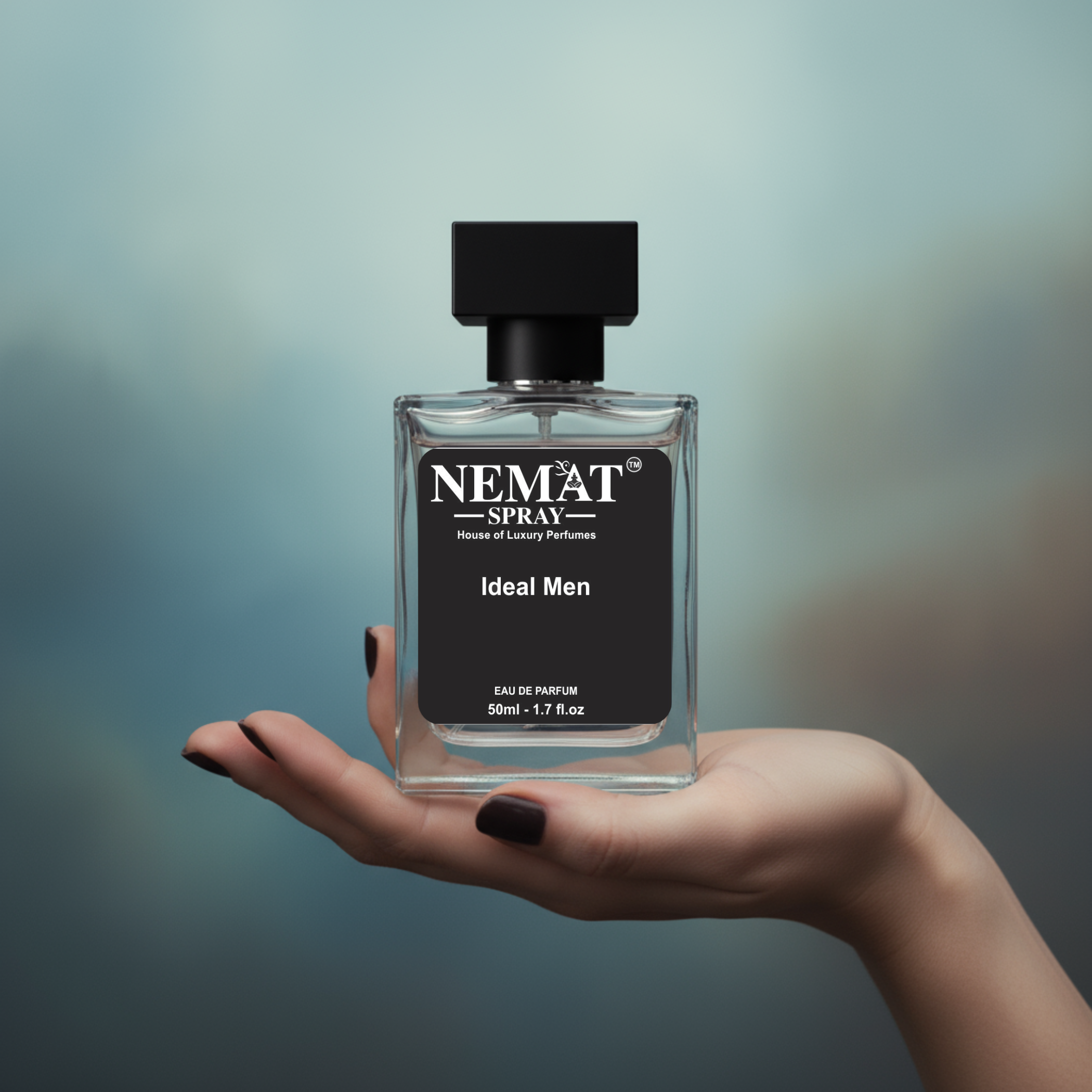 Nemat Ideal Men 50ml Eau de Parfum in a clear glass bottle with a black cap and label, held in a hand.