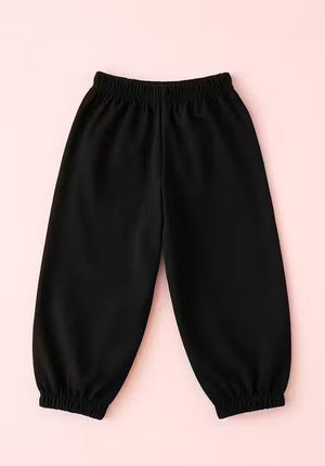 Black elastic-waist and elastic-calf pants laid flat on a light pink background.