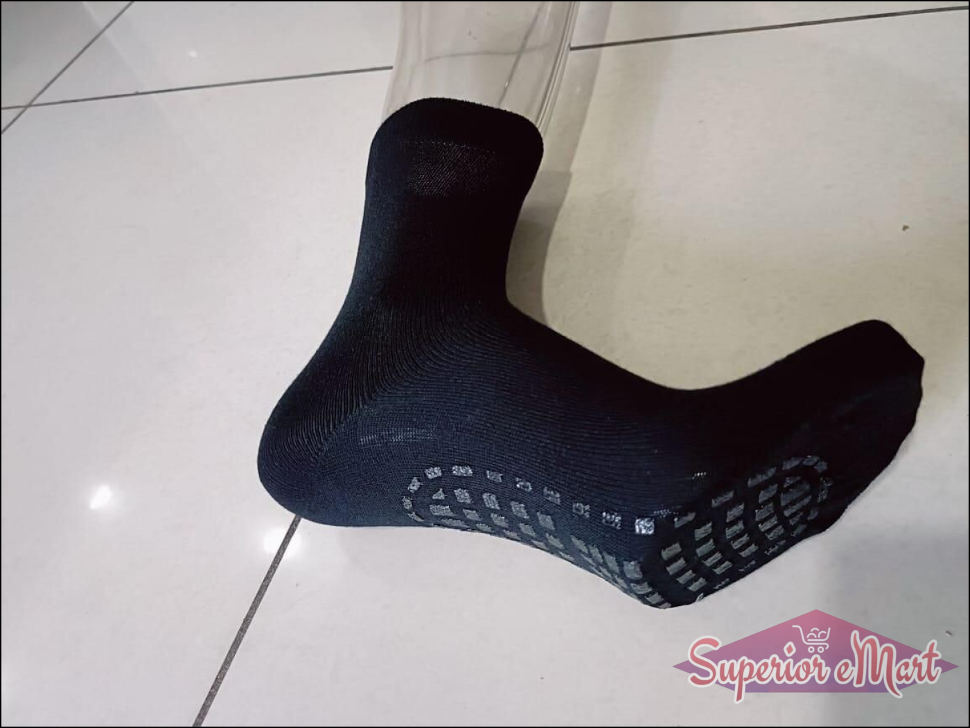Black ribbed crew sock with grey anti-slip grip pads on the sole, shown on a mannequin foot.