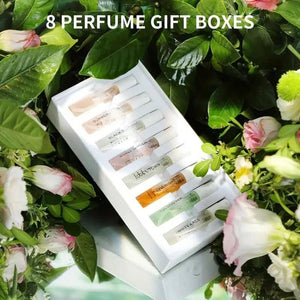 8 Perfumes Gift Box set with eight assorted fragrance bottles surrounded by green leaves and flowers