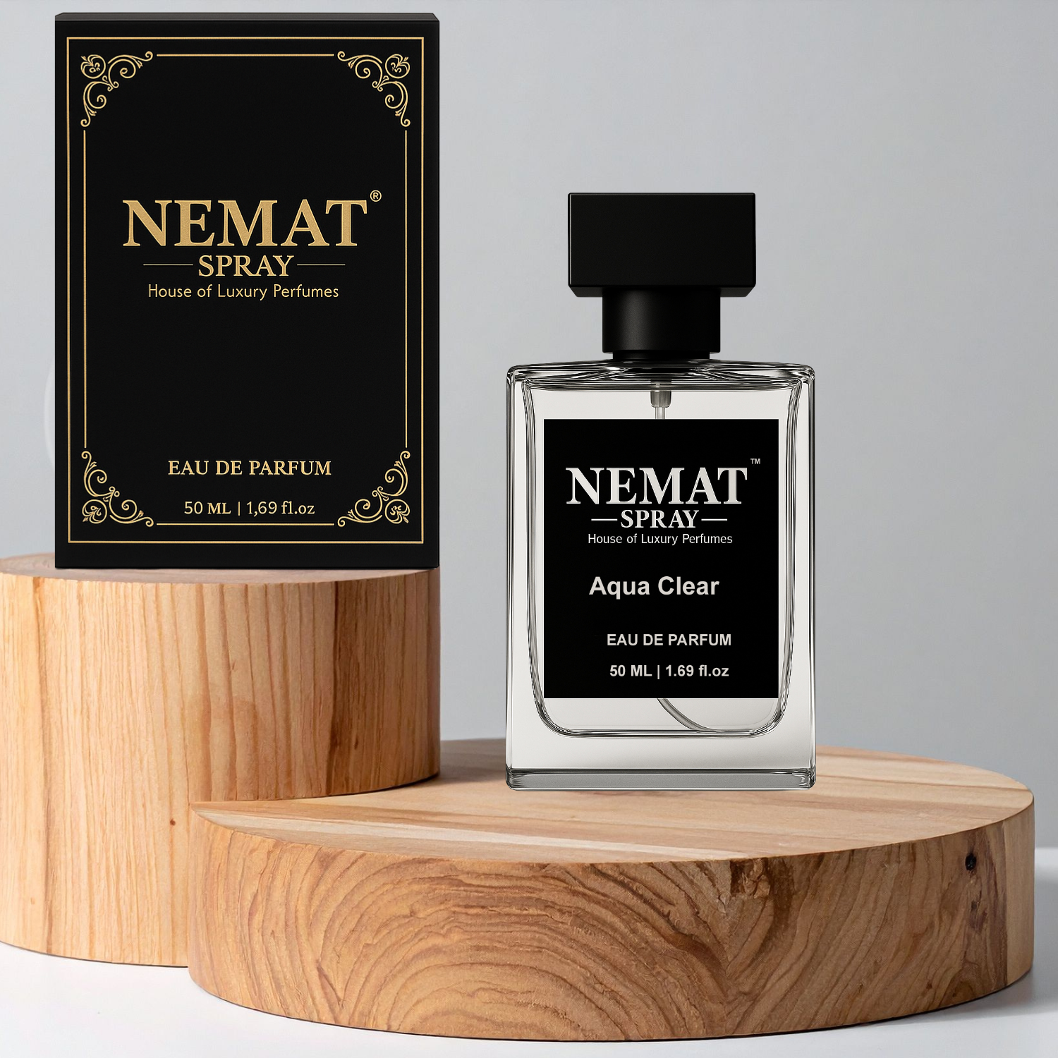 Nemat Aqua Clear 50ml perfume bottle and black gold-trimmed box displayed on wooden pedestals.