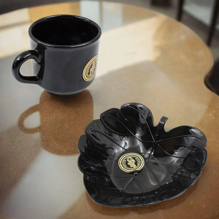 Elegant black ceramic tea cup and bowl set on a wooden table for stylish dining experiences