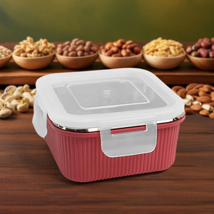 Red Apex Victor food container with white lid and secure latch placed on wooden surface with nuts in background
