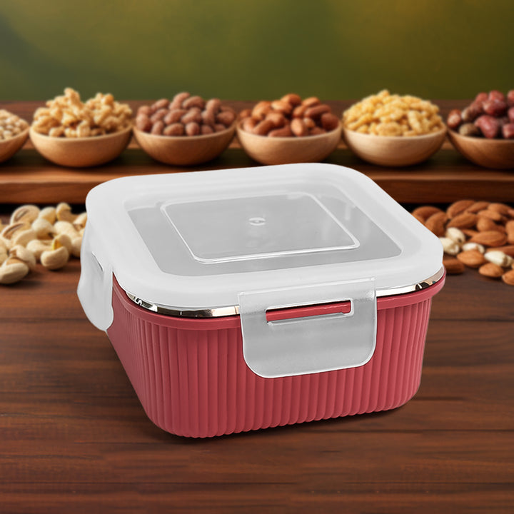 Red Apex Victor food container with white lid and secure latch placed on wooden surface with nuts in background