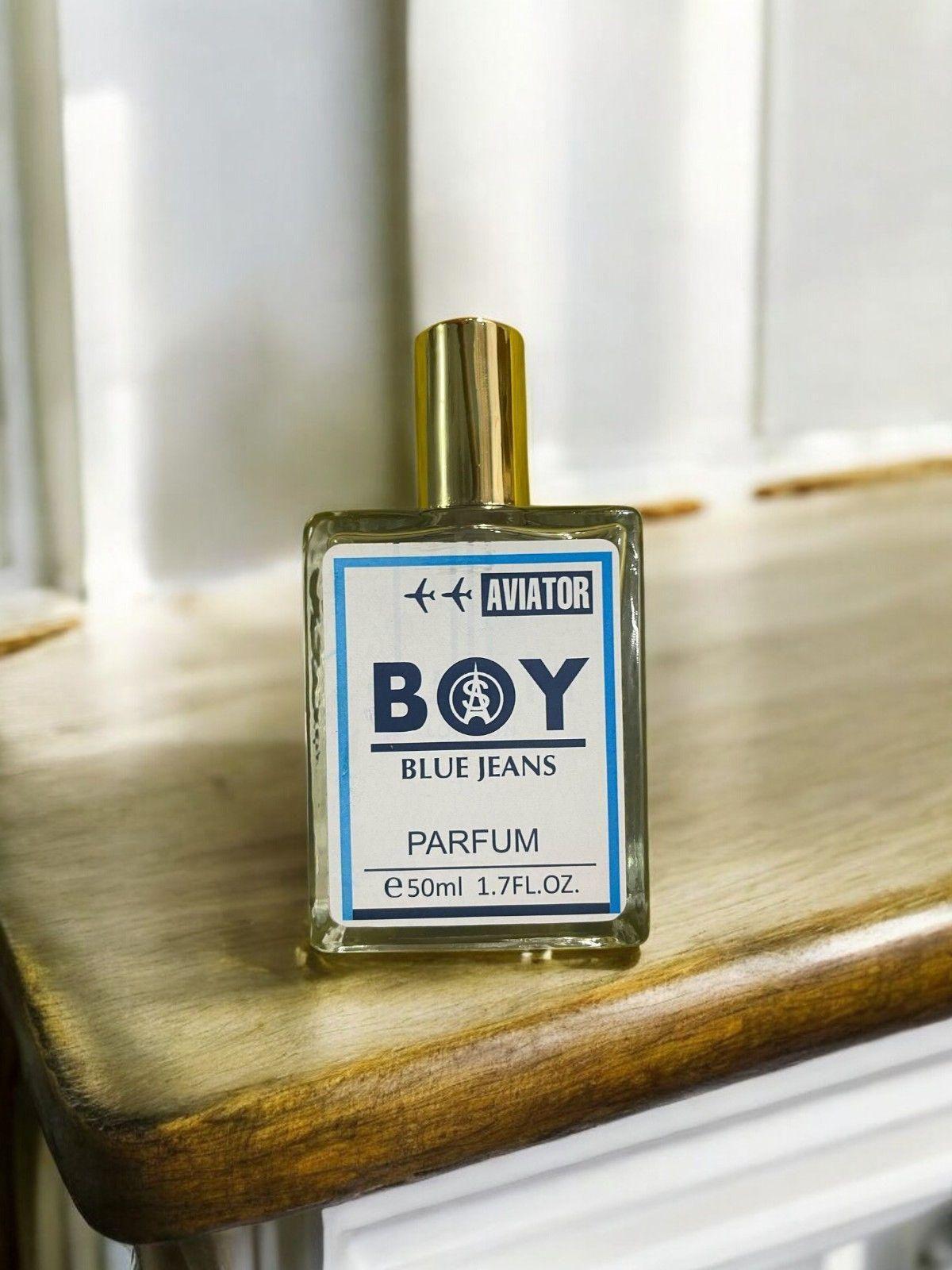 Aviator Boy Blue Jeans fragrance 50ml bottle on a wooden surface showcasing its stylish design