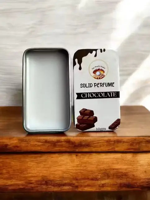Silver tin of Chocolate Solid Perfume by The Pearl Studio. Open to show white wax; lid features chocolate graphics.