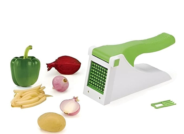A white and green manual vegetable grater and slicer set shown with toy vegetables including a green pepper, red onion, yellow potato, and purple onion on a white background.