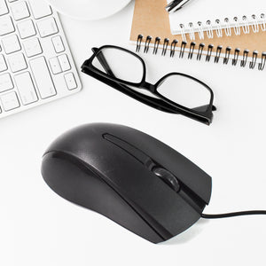 X2 computer mouse in black placed next to a keyboard, glasses, and a notebook