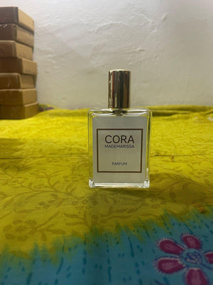 Cora Mademarissa perfume 50ml in a clear glass bottle with a stylish cap on a vibrant background