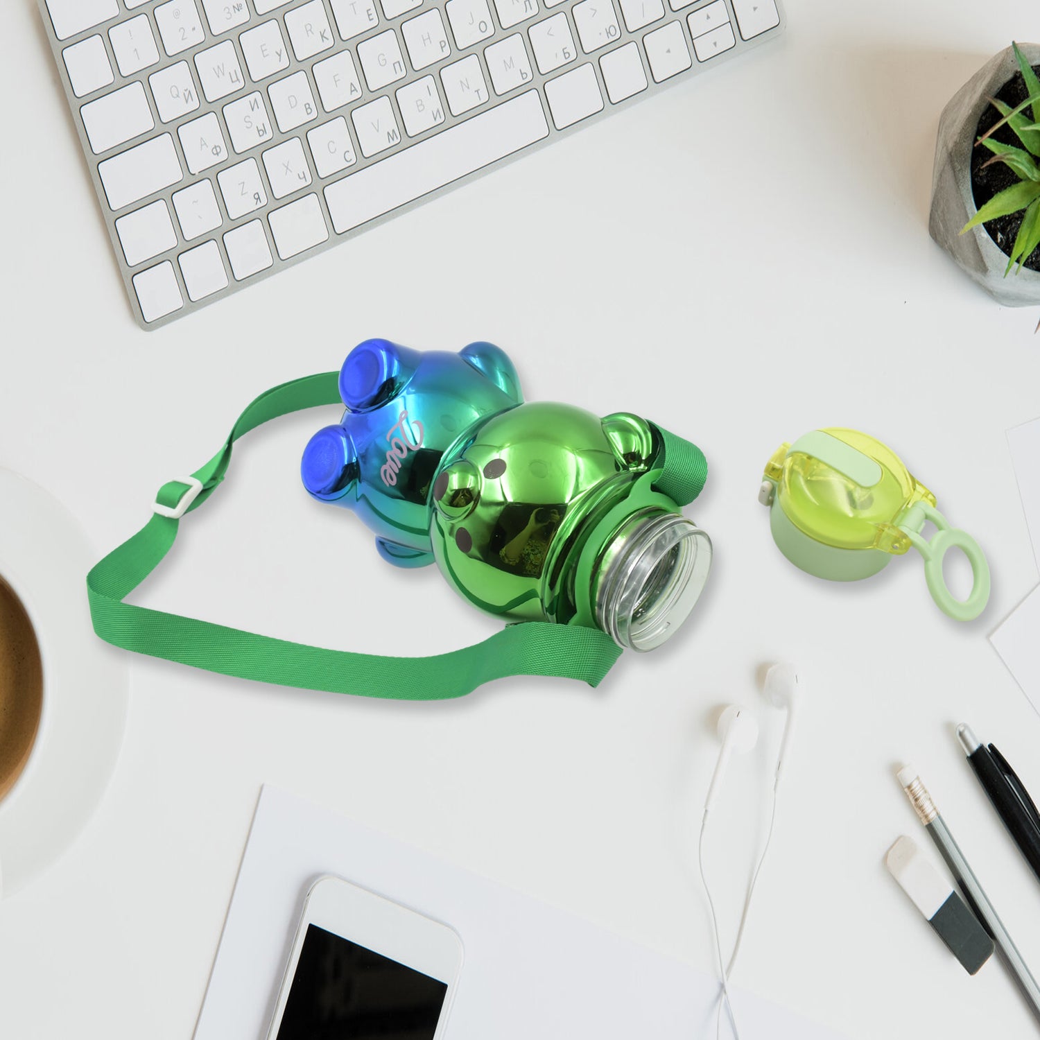 Cute kids water bottle with straw in shiny green bear design and green strap on desk with keyboard