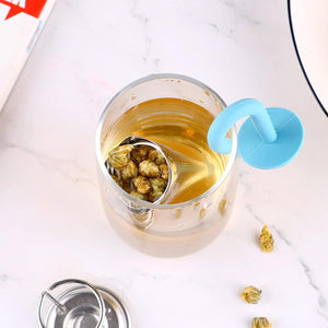 Cute umbrella tea strainer in blue, steeping flowers in a clear glass cup of tea