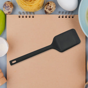 Black silicone dessert serving spatulas on a kitchen notepad surrounded by cooking ingredients