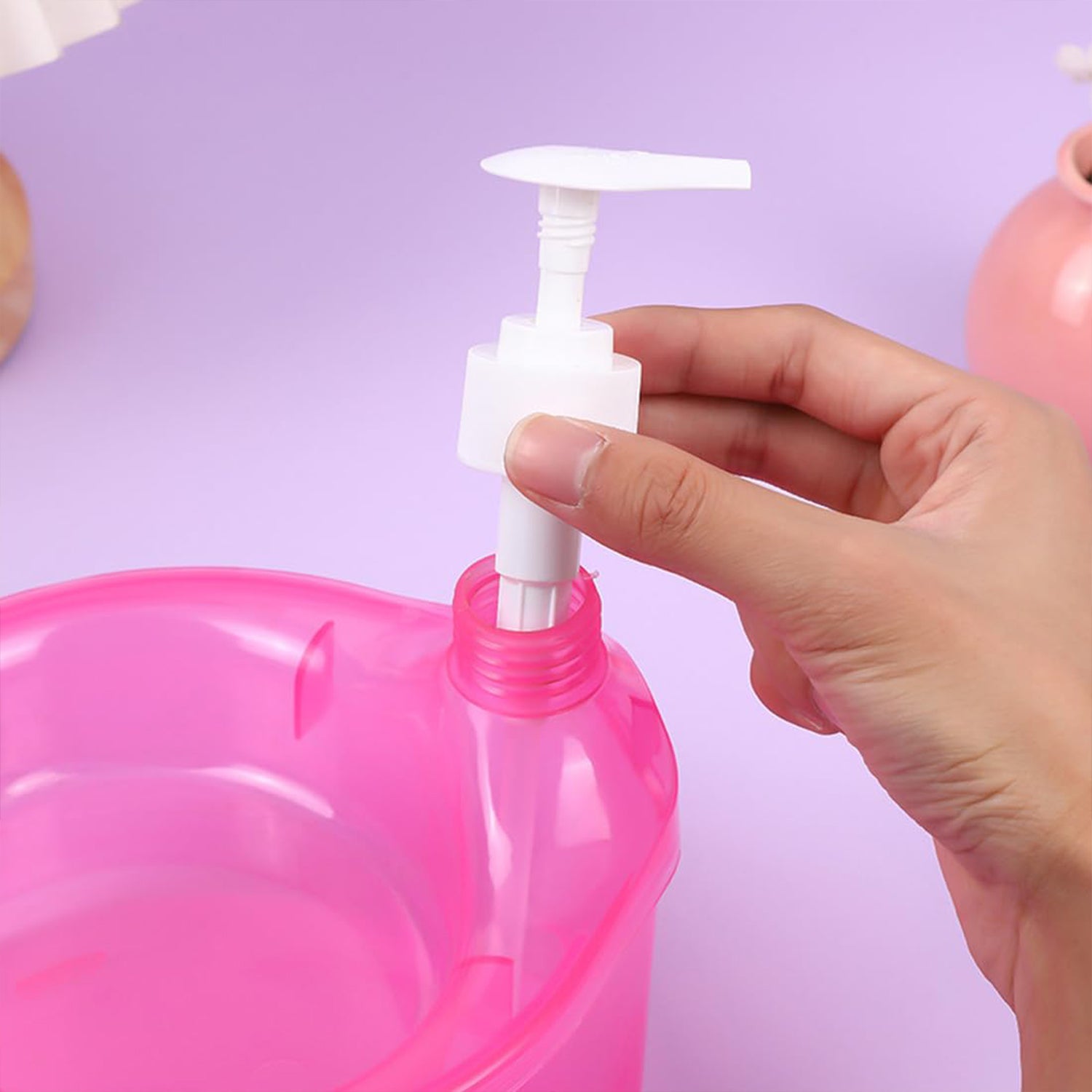 Hand installing pump on a pink double layer soap dispenser with sponge from Superior eMart