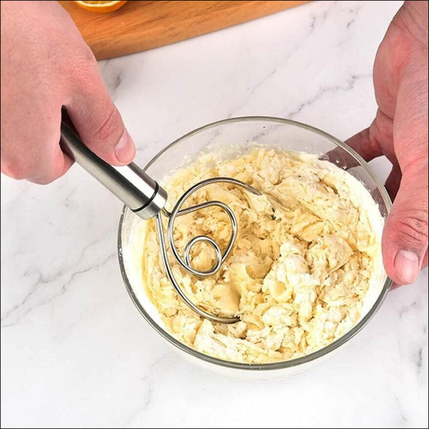 Superior eMart stainless steel dough whisk mixing batter in a glass bowl on a marble countertop