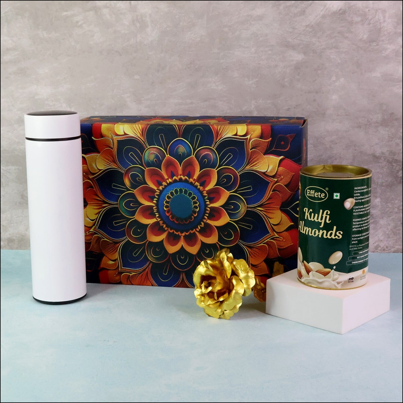 Festive gift hamper box featuring a decorative design, kulfi almonds, and a stylish white thermos