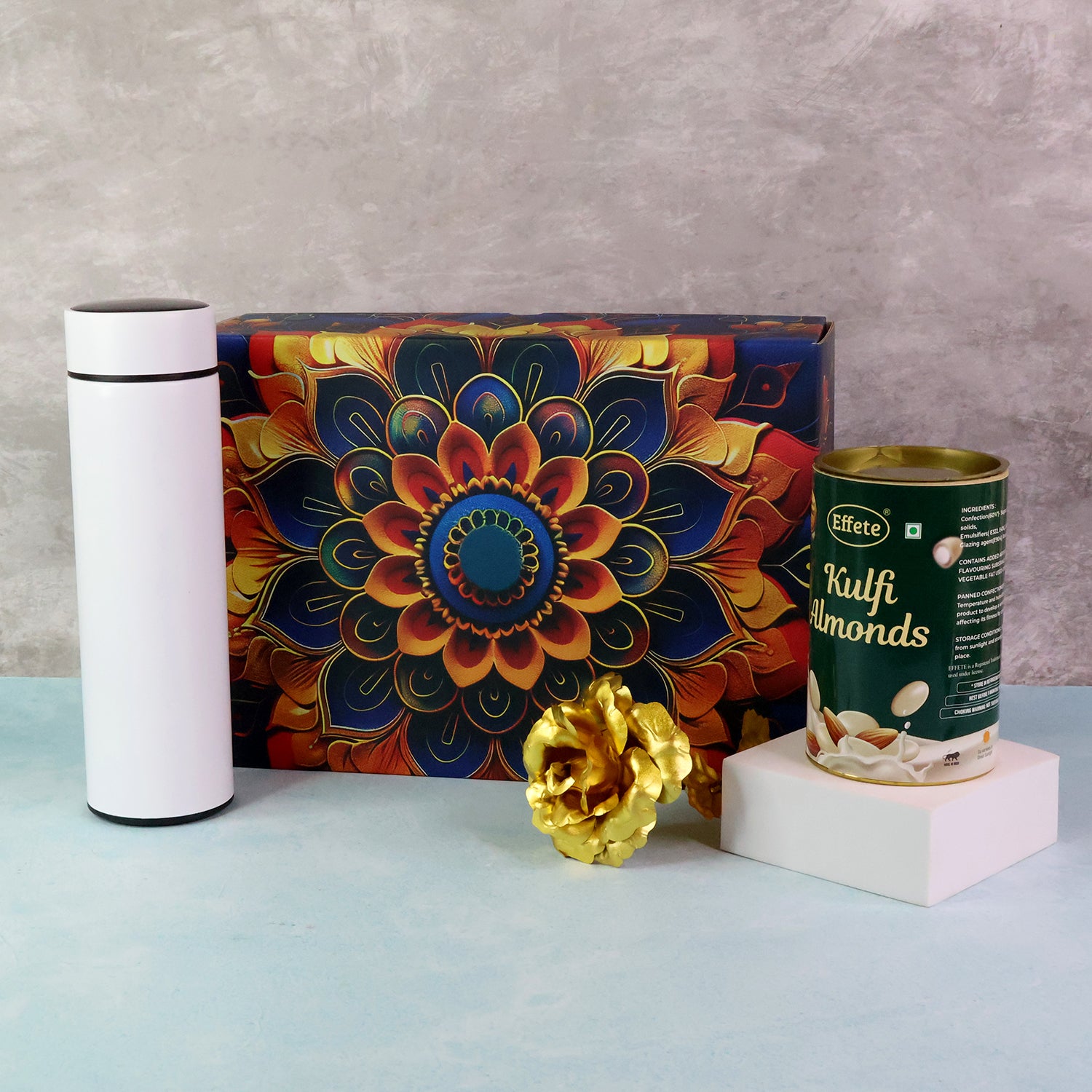 Festive gift hamper box featuring a decorative design, kulfi almonds, and a stylish white thermos