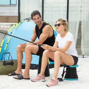 Two people sitting on a foldable height adjusting stool while fishing outdoors near a tent