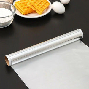 Heavy duty aluminum foil roll on a kitchen counter with cooking ingredients and waffles