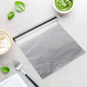 Heavy duty aluminum foil roll laid out on a kitchen countertop with fresh ingredients