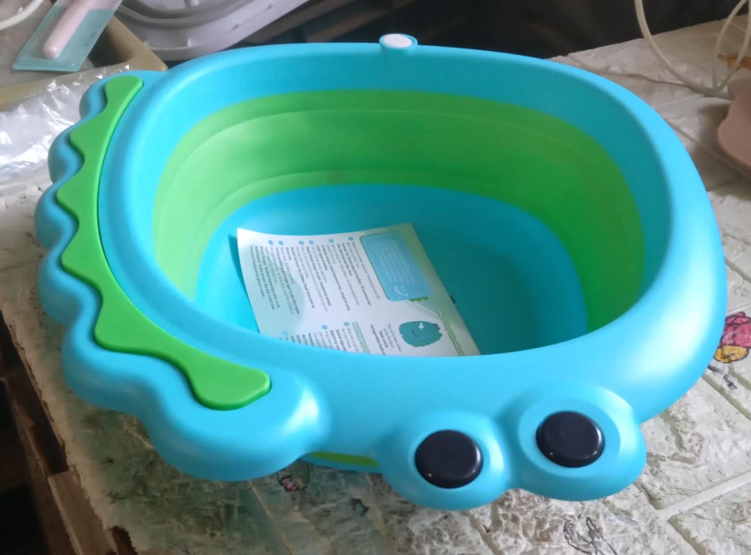 Frog shape baby wash basin in blue and green with user instructions for baby bath time