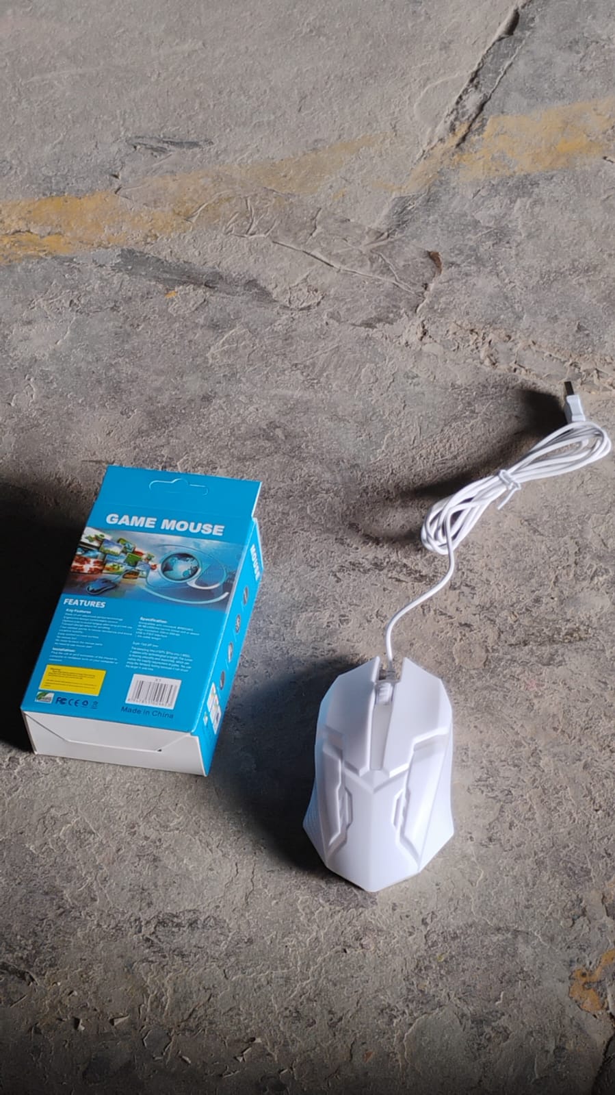 Superior eMart gaming mouse with lighting in white next to its packaging on a textured surface