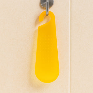 Bright yellow garlic and ginger grater tool hanging on a kitchen wall for easy access