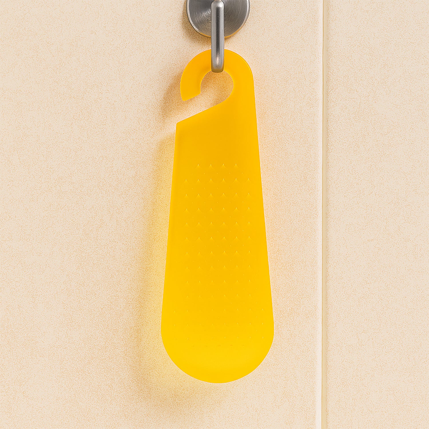 Bright yellow garlic and ginger grater tool hanging on a kitchen wall for easy access
