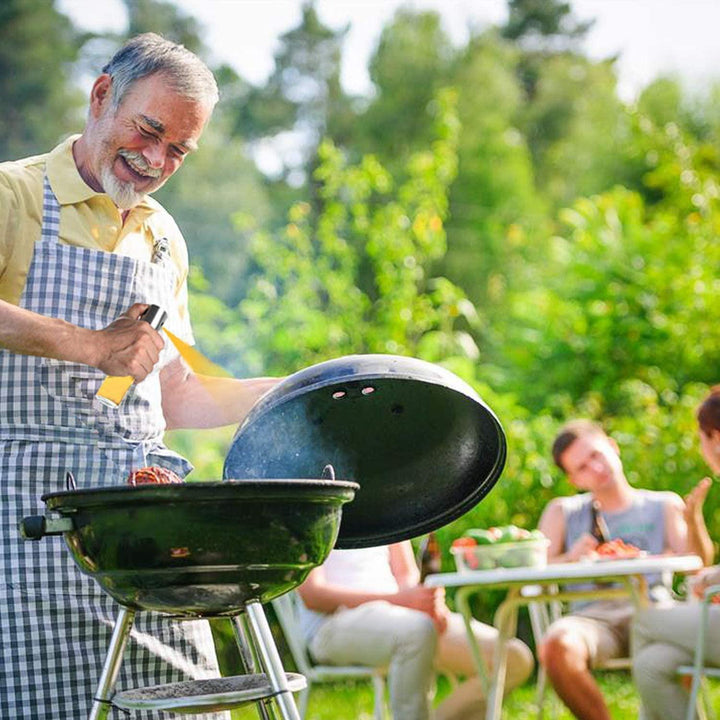 Man grilling outdoors using a glass oil sprayer for cooking, with friends enjoying nearby