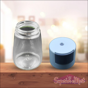 Clear glass salt dispenser for cooking with a blue cap for easy pouring and fine control