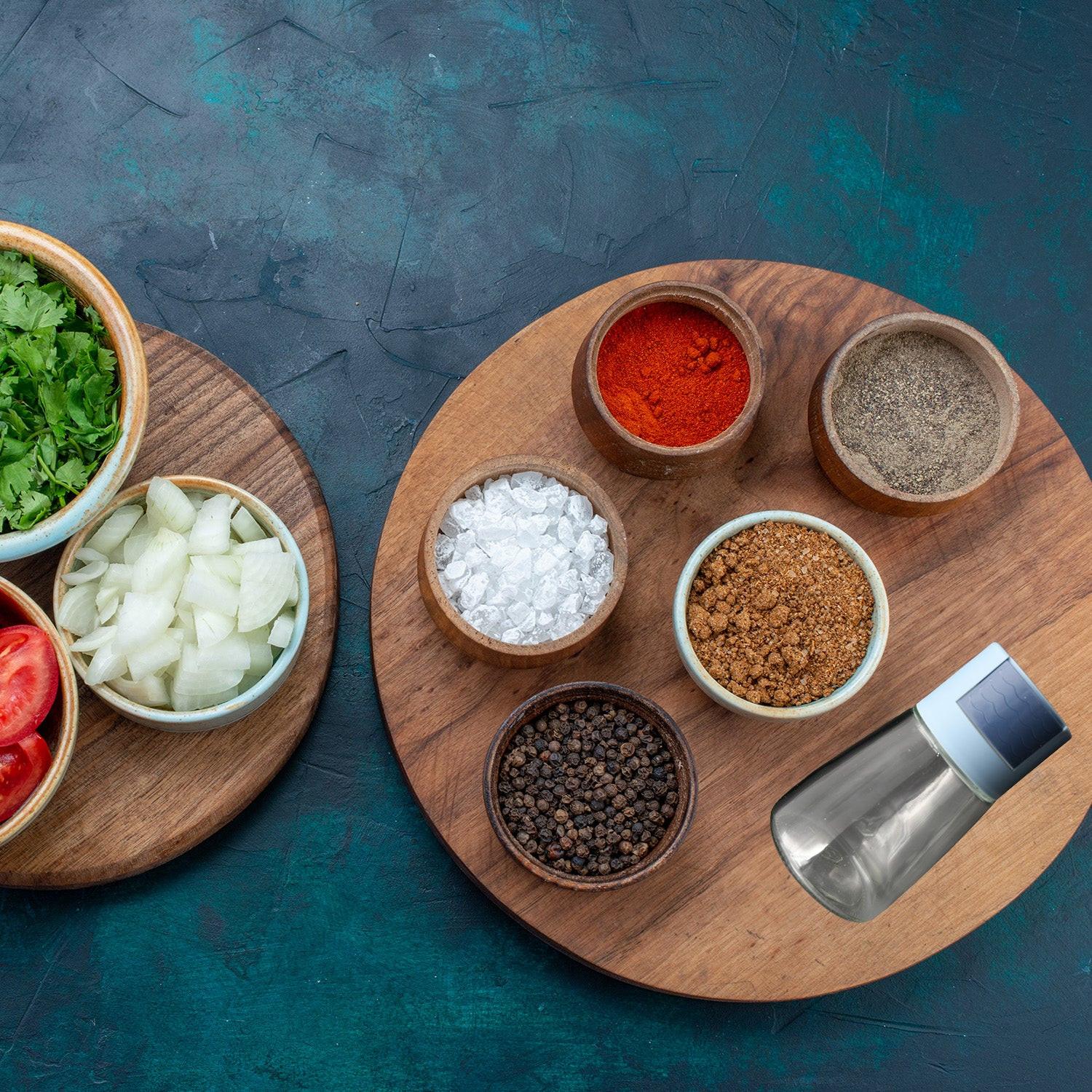 Glass salt dispenser for cooking displayed on a kitchen table with various spices and ingredients