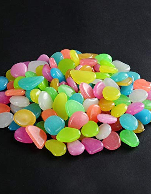Colorful glow in the dark garden pebbles in various shapes and bright colors on a black background