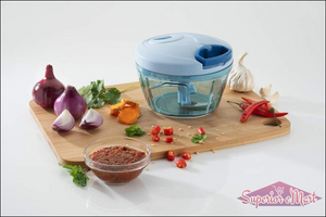 Handheld vegetable chopper in blue with chopped ingredients and spices on a wooden cutting board