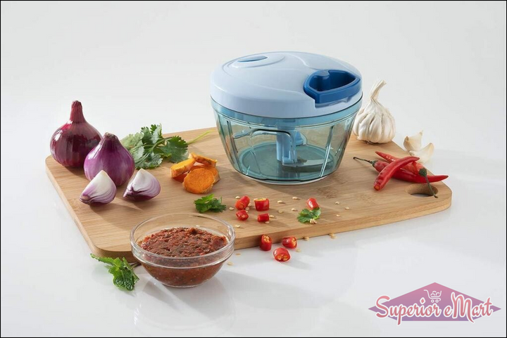 Handheld vegetable chopper in blue with chopped ingredients and spices on a wooden cutting board
