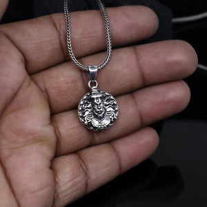 Hanuman facelocket necklace in silver with intricate detailing, held in a hand for scale