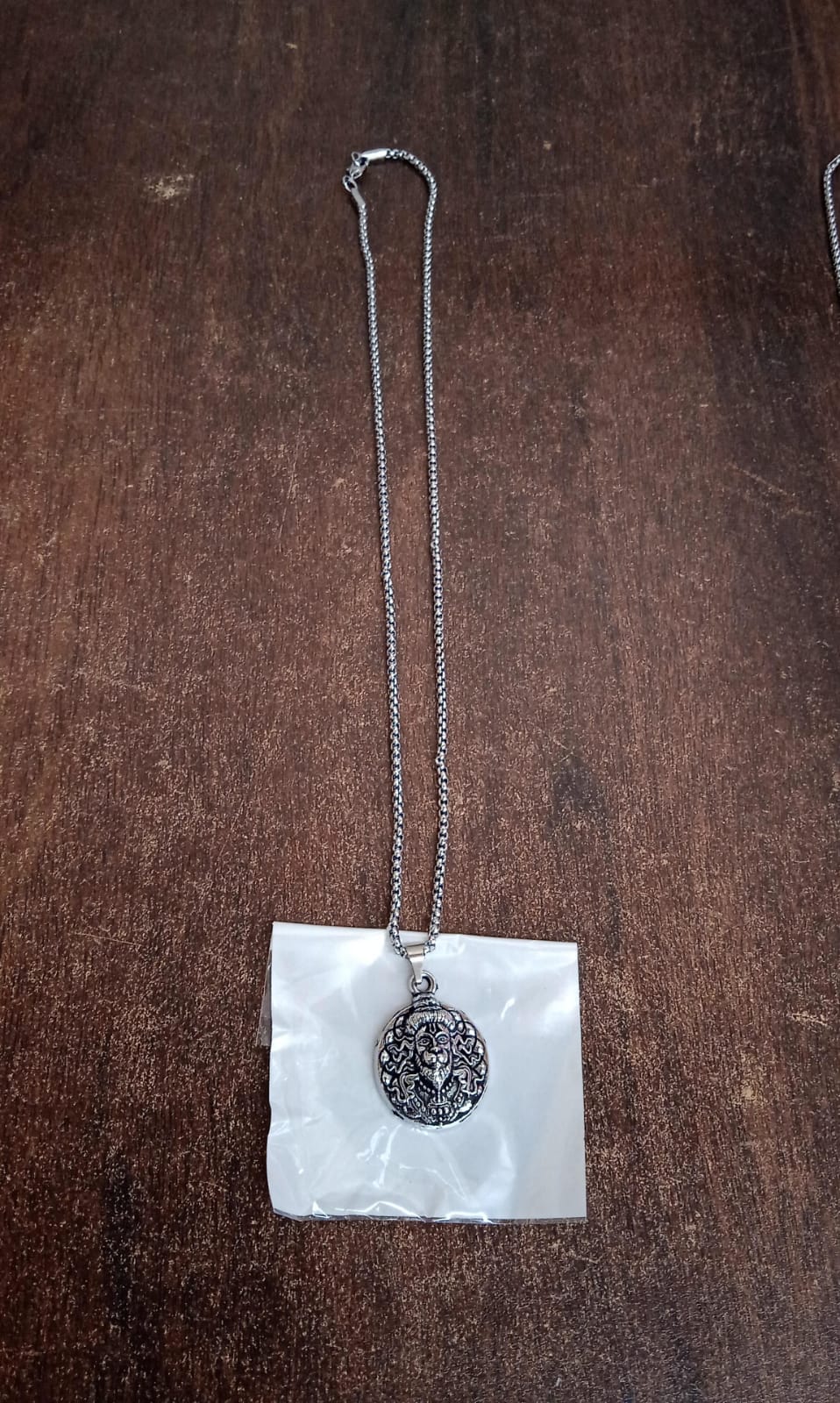 Hanuman facelocket necklace with detailed pendant and silver chain over a white background