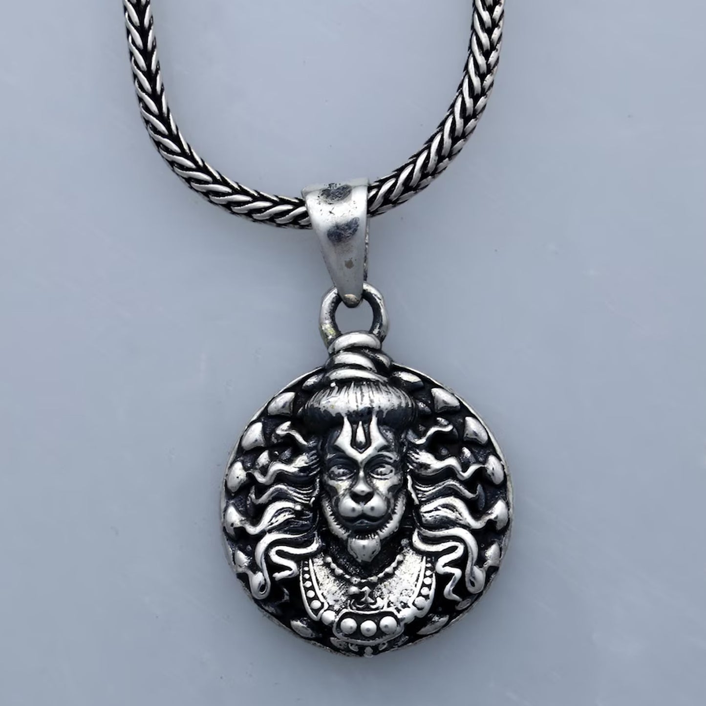 Hanuman facelocket necklace with intricate silver design and braided metal chain