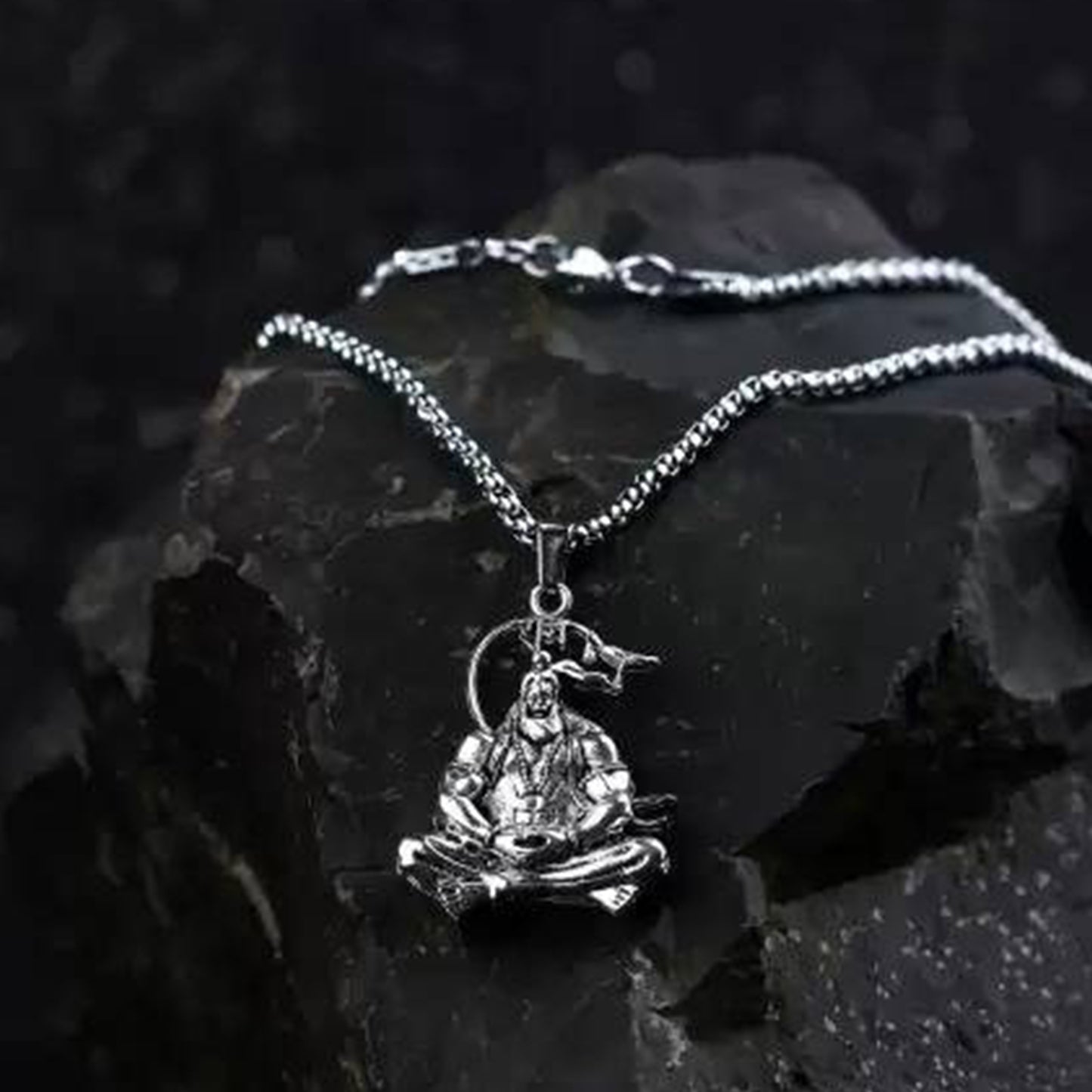 Silver Hanuman Ji pendant necklace on a sleek chain resting on a dark stone surface