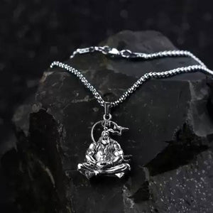 Silver Hanuman Ji pendant necklace on a sleek chain resting on a dark stone surface