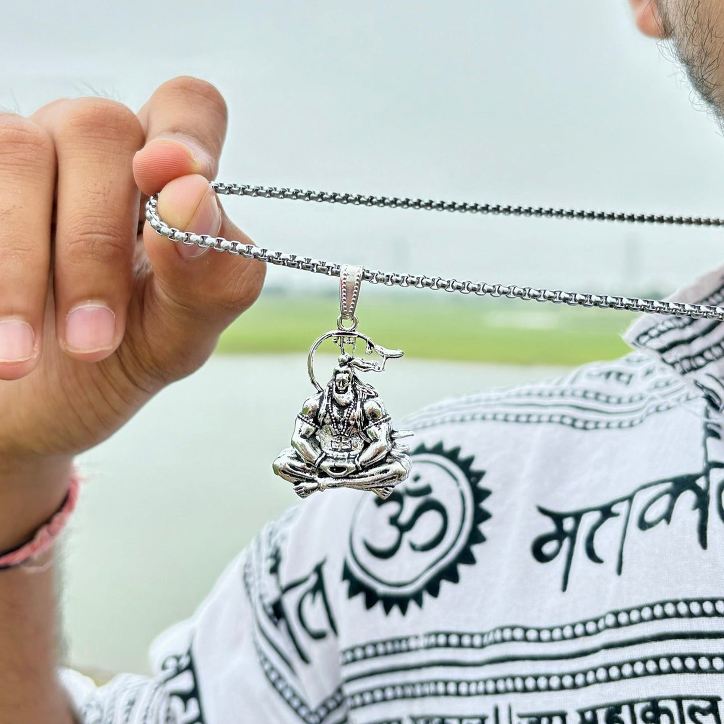 Silver Hanuman Ji pendant necklace displayed by a person with traditional attire