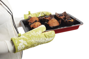 Green heat proof oven glove with floral design, holding a tray of baked muffins